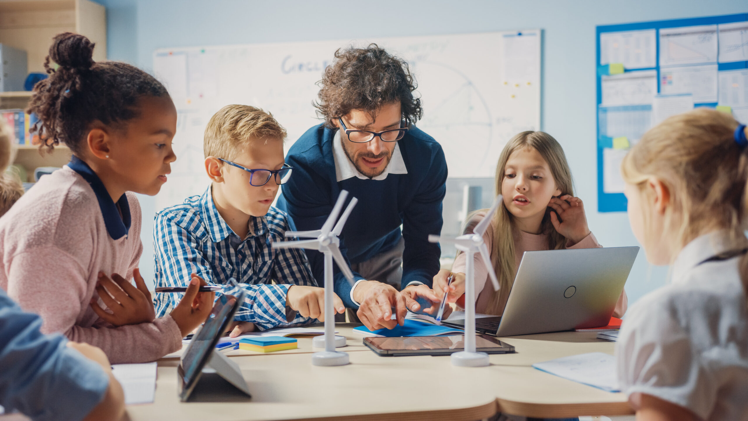 Elementary,School,Classroom:,Enthusiastic,Teacher,Holding,Tablet,Computer,Explains,To